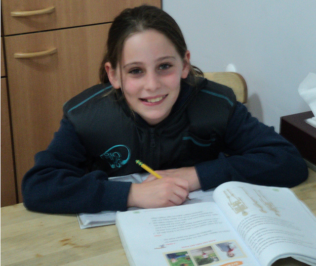 A child doing homework while wearing the BioHug.