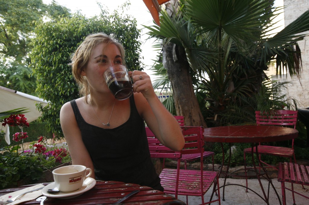A young woman drinks coffee at a cafe in Tel Aviv. Photo by Flash90.