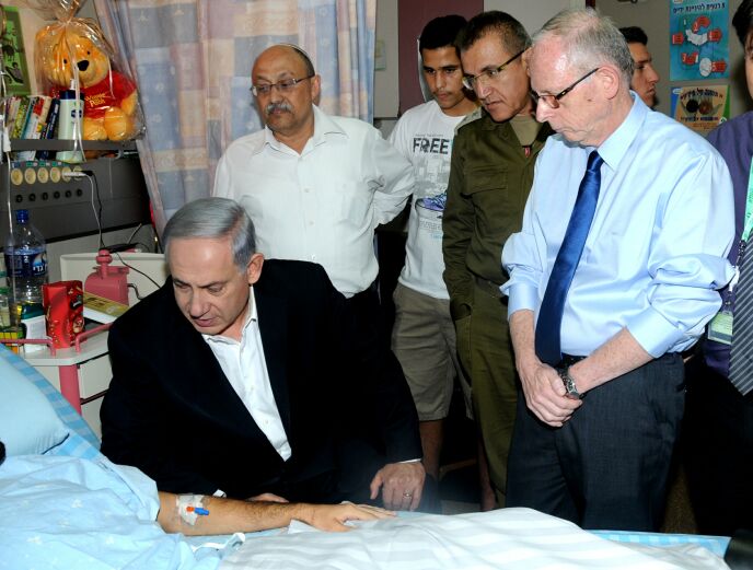 Soroka Director Ehud Davidson, right, with Prime Minister Netanyahu at the bedside of a wounded soldier. Photo courtesy of Soroka Medical Center