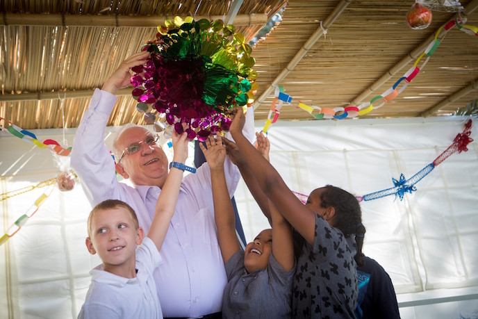 Rivlin getting help decorating his sukkah. Photo by Miriam Alster/FLASH90